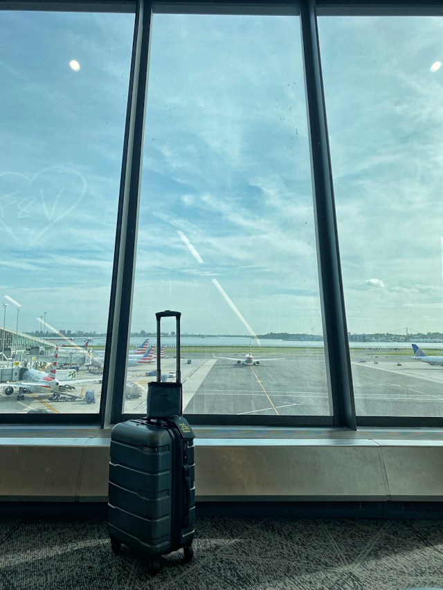 Suitcase beside an airport window overlooking aircraft